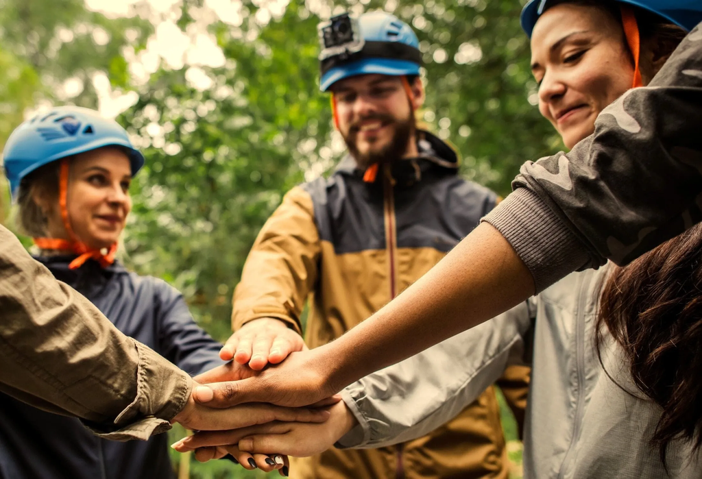Outdoor team-building exercise with work colleagues placing hands in the centre